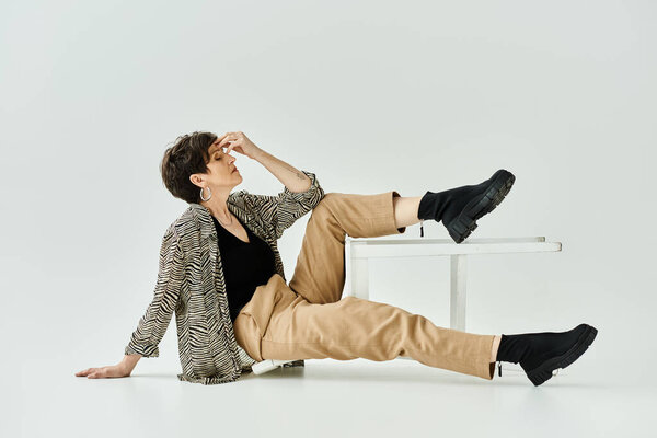 Женщина средних лет в повседневной одежде удобно сидит на стильном белом стуле в студии.