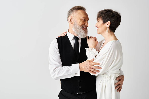 A middle aged bride and groom in wedding gowns celebrating their special day in a studio setting.