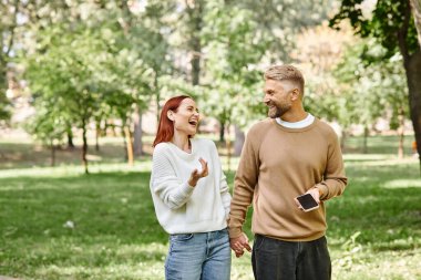 Gündelik giysiler içinde yetişkin bir çift huzur parkında yürüyüş yapıyor..