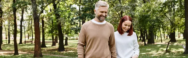 Bir adam ve bir kadın günlük giysiler içinde yemyeşil bir ormanda geziniyorlar..