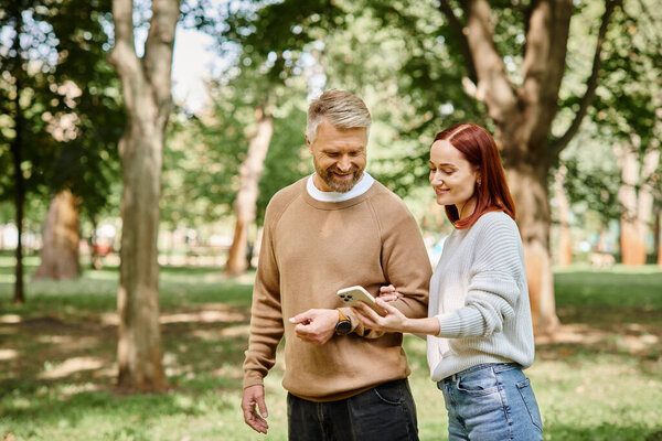 A man and a woman in casual attire, taking a stroll in a peaceful park.