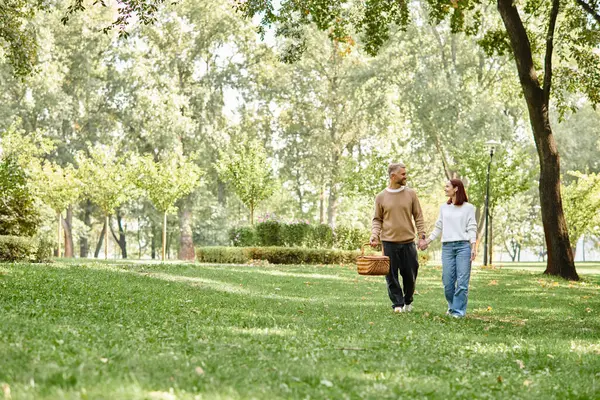 stock image A loving couple in casual attire leisurely walking through a serene park.