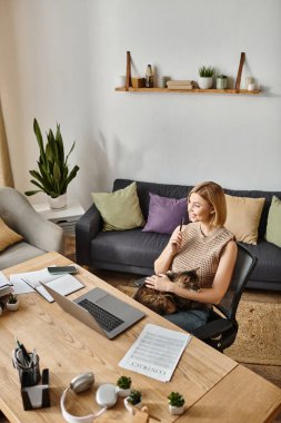Kısa saçlı bir kadın, bir kanepede, kucağında memnun bir kediyle, huzur dolu bir anın tadını çıkarıyor..