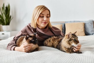 A woman with short hair peacefully relaxes on a bed alongside two content cats in a cozy home setting. clipart