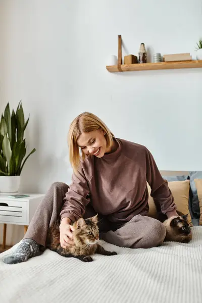 短い髪の女性がベッドに座り 猫を飼う — ストック写真