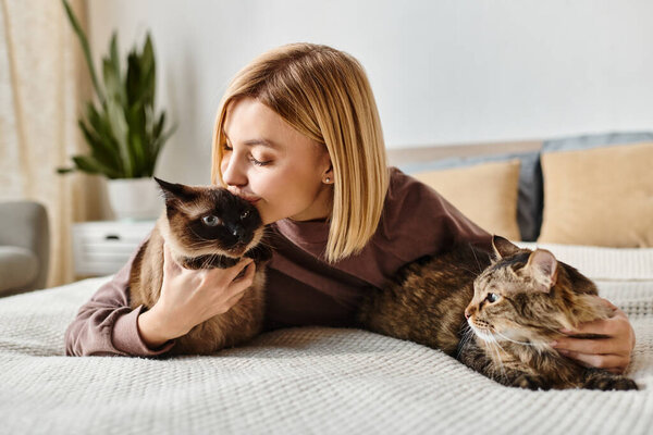 A woman with short hair lays peacefully on a bed, holding a content cat in her arms.
