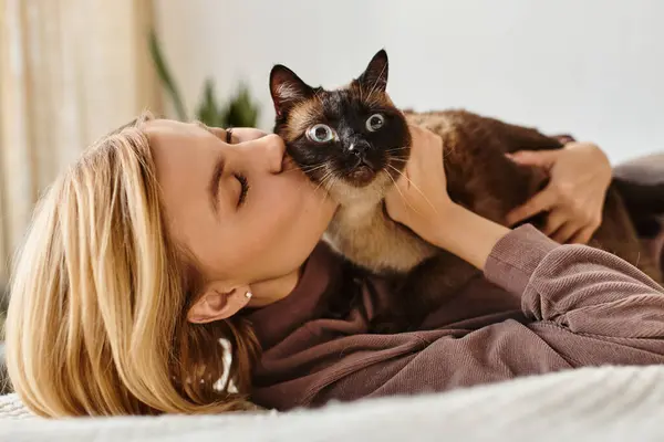 ベッドに横たわっている短い髪の女性は 穏やかな絆と愛情の瞬間に彼女の猫に優しくキスします — ストック写真