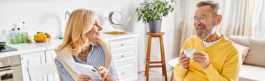 A mature loving couple standing in a cozy living room, sharing a moment of intimacy and connection. clipart