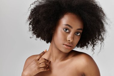 Stüdyoda kıvırcık saçlı Afro-Amerikan bir kadın portre için poz veriyor..