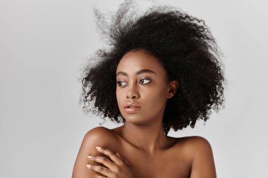Büyüleyici kıvırcık saçlı Afro-Amerikan bir kadın kameradan gözünü kaçırıyor..