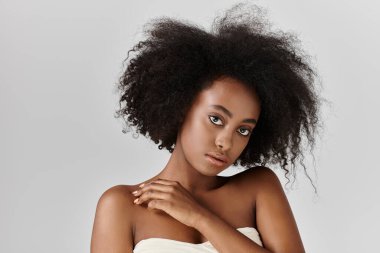 Kıvırcık saçlı ve stüdyo ortamında poz veren Afro-Amerikan bir kadın..