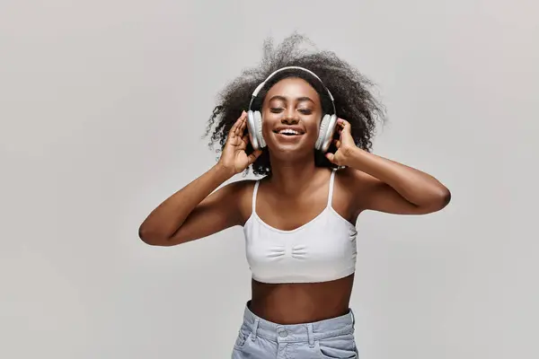 Młoda Afroamerykanka Kręconymi Włosami Słucha Uważnie Przez Słuchawki Białej Bluzce — Zdjęcie stockowe