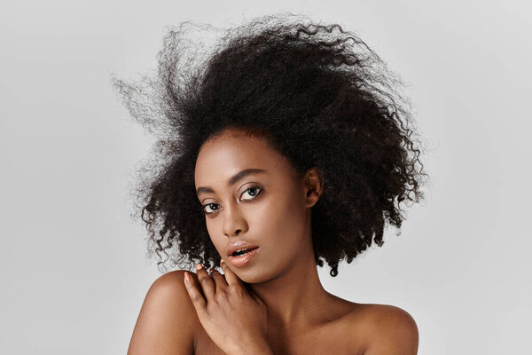 A young African American woman with curly hair posing for a portrait, showcasing her luxurious hair.
