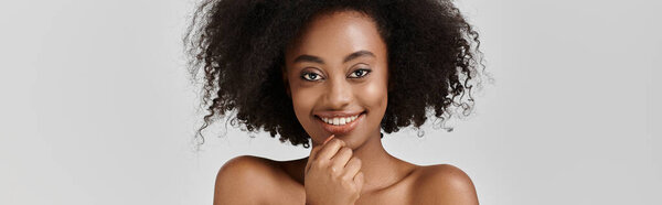 A stylish young African American woman with a curly afro hairdo strikes a pose in a studio setting.