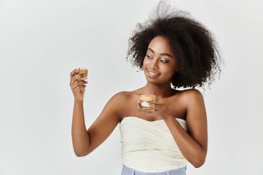 Kıvırcık saçlı, kremalı genç bir Afrikalı Amerikalı kadın.