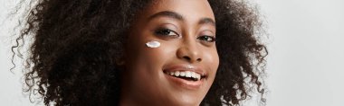 A beautiful young African American woman with curly hair, conveying pure happiness with a bright smile on her face. clipart