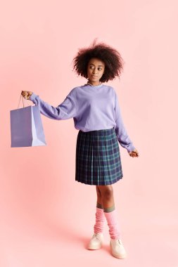 Etek giymiş şık bir Afro-Amerikalı kadın bir alışveriş çantası tutuyor, bir stüdyo ortamında moda ve zarafet yayıyor..
