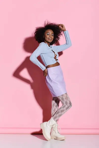 活気に満ちたピンクの壁の前に優雅なポーズを打つカーリー髪のスタイリッシュな若いアフリカ系アメリカ人女性 — ストック写真