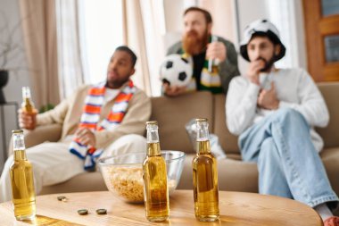 Üç farklı, neşeli adam masanın etrafında biraraya gelip bira şişelerini paylaşmaktan zevk alıyor..