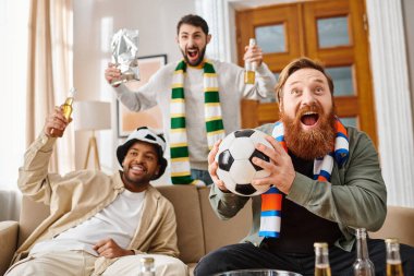 Three cheerful, diverse men in casual attire sitting on a couch, happily holding soccer balls in home setting. clipart