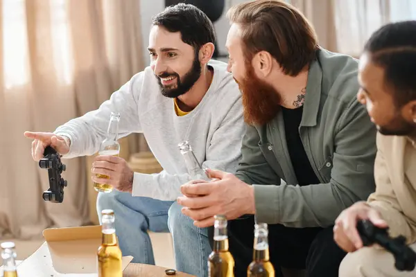 stock image Three cheerful, interracial men enjoy a casual gathering, laughing and chatting over bottles of beer on a table.