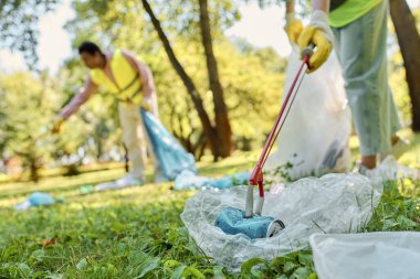 A diverse, harmonious couple in safety vests, gloves, and with a lawn mower, maintaining the parks greenery. clipart