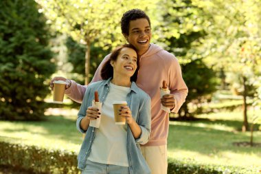 Canlı giyinmiş bir çift, kahve fincanlarını tutarken birbirlerine sarılıyorlar..