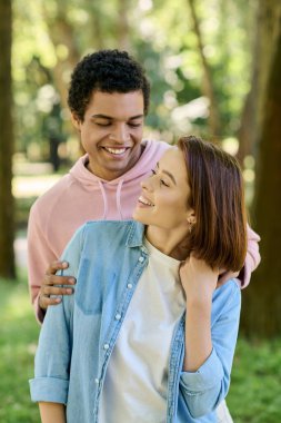 Canlı giyinmiş bir adam, parkın yemyeşil yeşilliği altında sevgi dolu bir kadın, derin bir şefkat hissi yayıyor..