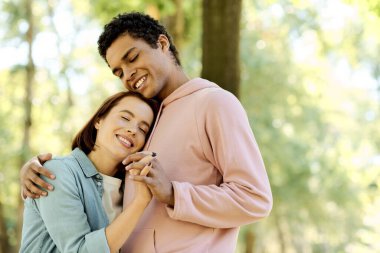 Değişik renklerde giyinmiş bir çift park ortamında sıcak bir kucaklaşmayı paylaşıyor, sevgi ve bağ kuruyorlar..