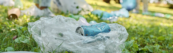 Банка содовой лежит на пластиковом пакете в пышной траве парка, контрастируя с зеленым фоном..