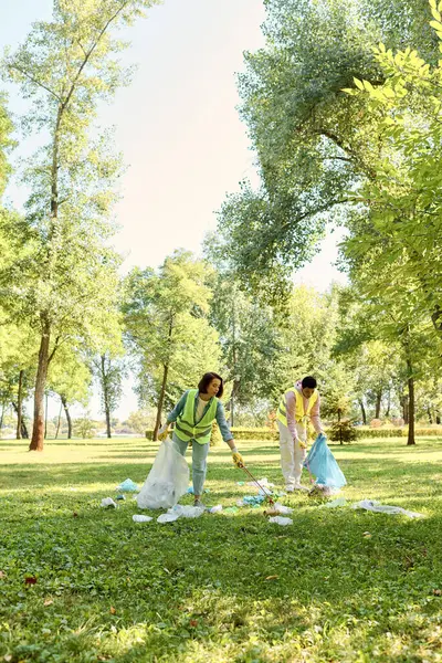 穿着安全背心和手套的不同夫妇站在一片茂盛的绿地上 体现了社会责任感和团队精神 — 图库照片