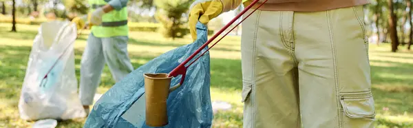 stock image Diverse loving couple, wearing safety vests and gloves, stand together in a field, cleaning the park with unity and teamwork.