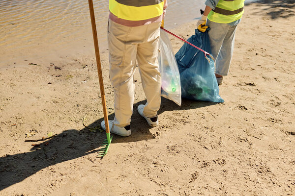 Разнообразная трудолюбивая пара, страстно очищающая парк в перчатках безопасности.