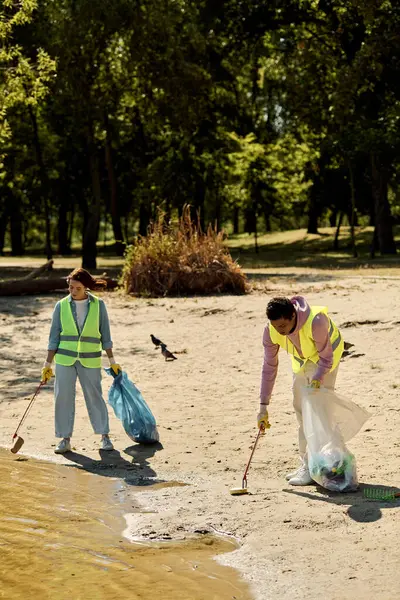 安全ベストと手袋の社会的に活発で多様なカップル 砂に立って公園を一緒に掃除する — ストック写真