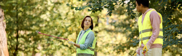 Разнообразная любящая пара, одетая в спасательные жилеты и перчатки, стоящая в тихом лесу.