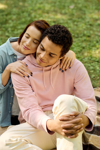 Разнообразная, любящая пара в яркой одежде сидит вместе, наслаждаясь спокойным моментом в парке.