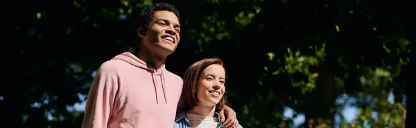 Stock image A man and a woman, dressed vibrantly, stand side by side in a park, showcasing love and togetherness.