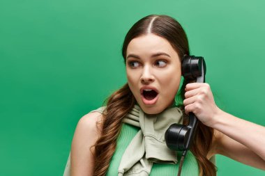 20 'li yaşlarda şok olmuş genç bir kadın kulağına bir retro telefon dayayıp dikkatle dinliyor..