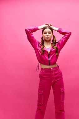 Pembe elbiseli bir kadın pembe arka planlı şık bir stüdyo ortamında poz veriyor..