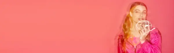 一位穿着粉红衣服的年轻女子优雅地捧着迪斯科舞会 在一个有着粉红背景的工作室里营造出一种梦幻迷人的氛围 — 图库照片