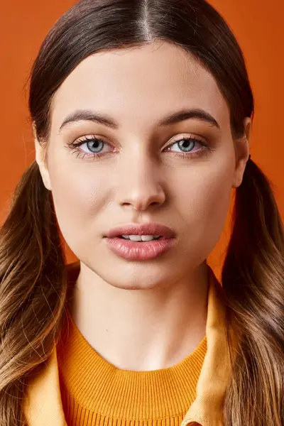 20 'li yaşlarda şık bir kadın, uzun saçlı parlak sarı bir süveter giyiyor..