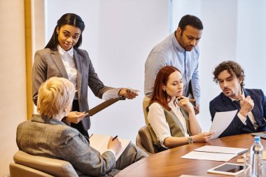 Diverse group of business professionals engaged in a meeting around a conference table. clipart