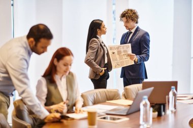 Multiracial business professionals collaborating around conference table. clipart