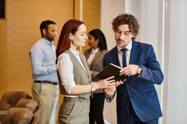 Bir adam ve bir kadın takım elbiseli bir adamın önünde duruyor..