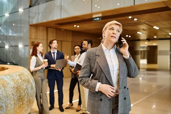 Bir kadın, kendi cep telefonunu kullanarak ırklar arası bir iş grubuna güvenle hitap ediyor..