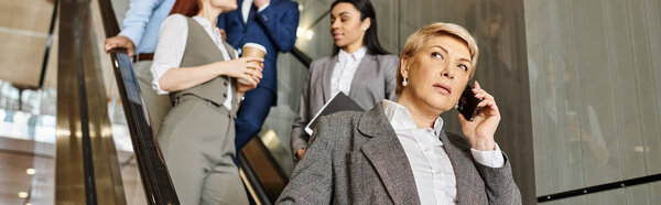 A woman multitasks, talking on a cell phone while walking down an escalator.
