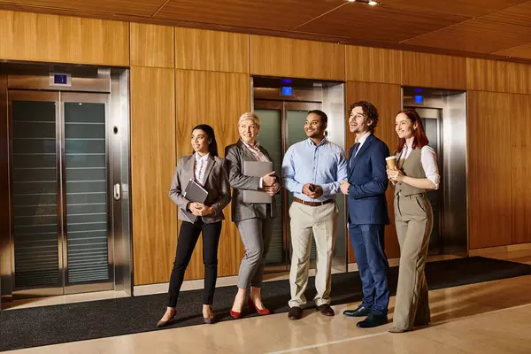 stock image A diverse group of business professionals standing together in front of elevator doors.