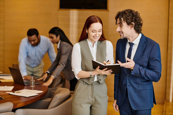 Межрасовые мужчина и женщина стоят перед столом и обсуждают бизнес.