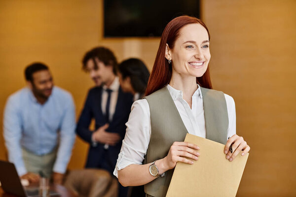 A woman stands holding a folder in front of a diverse group of business people.