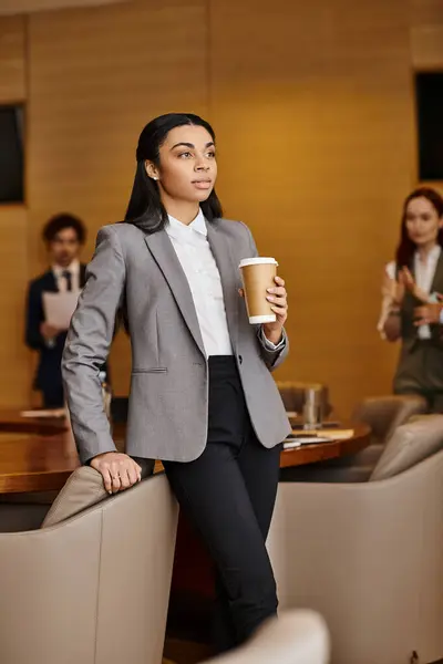 An African American woman in a business suit holding a cup of coffee.